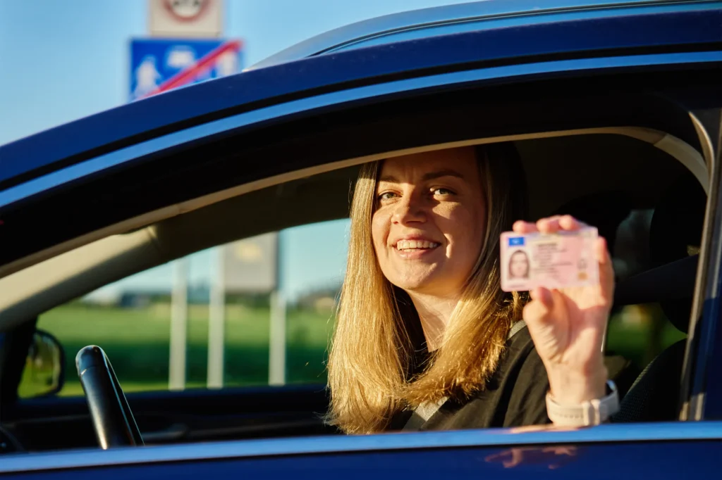 happy woman holding driver license in car 2025 03 14 13 22 37 utc